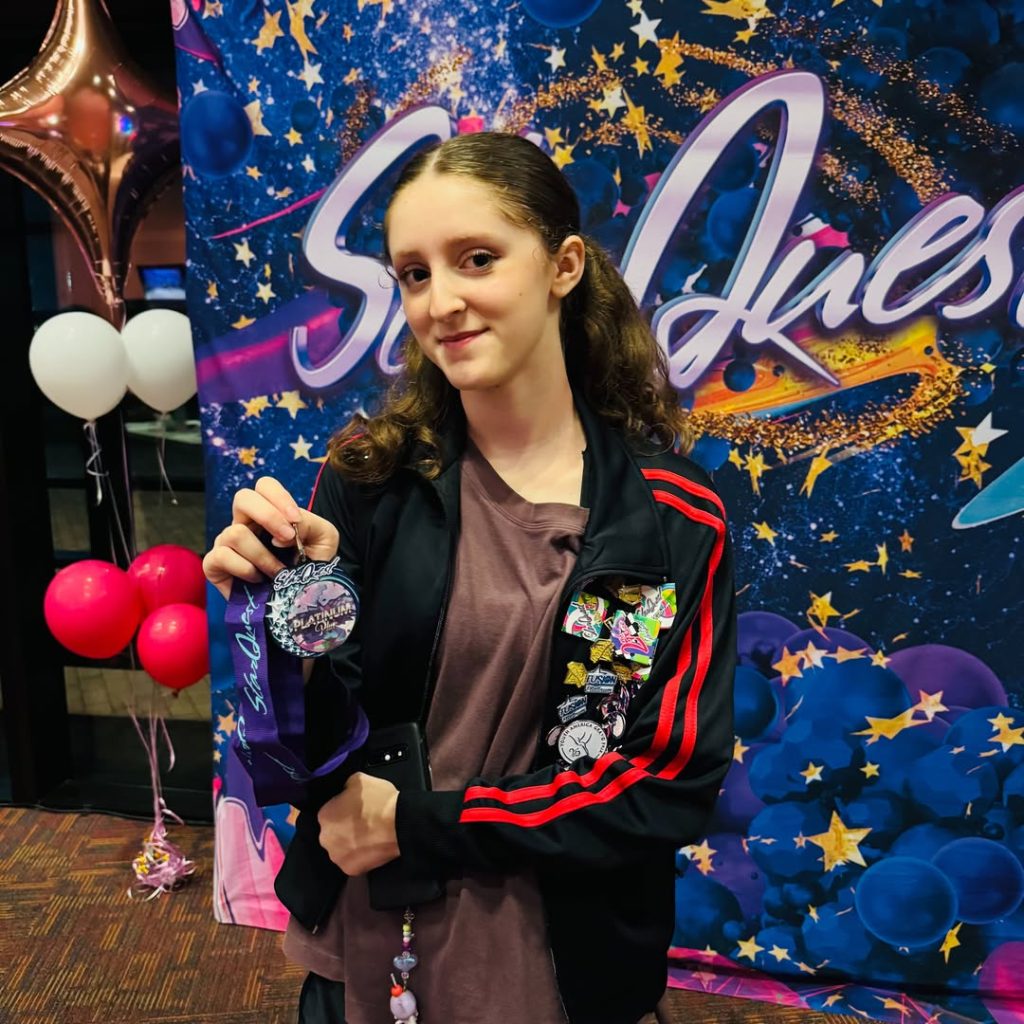 Sasha Benton holding a StarQuest Platinum Plus Award